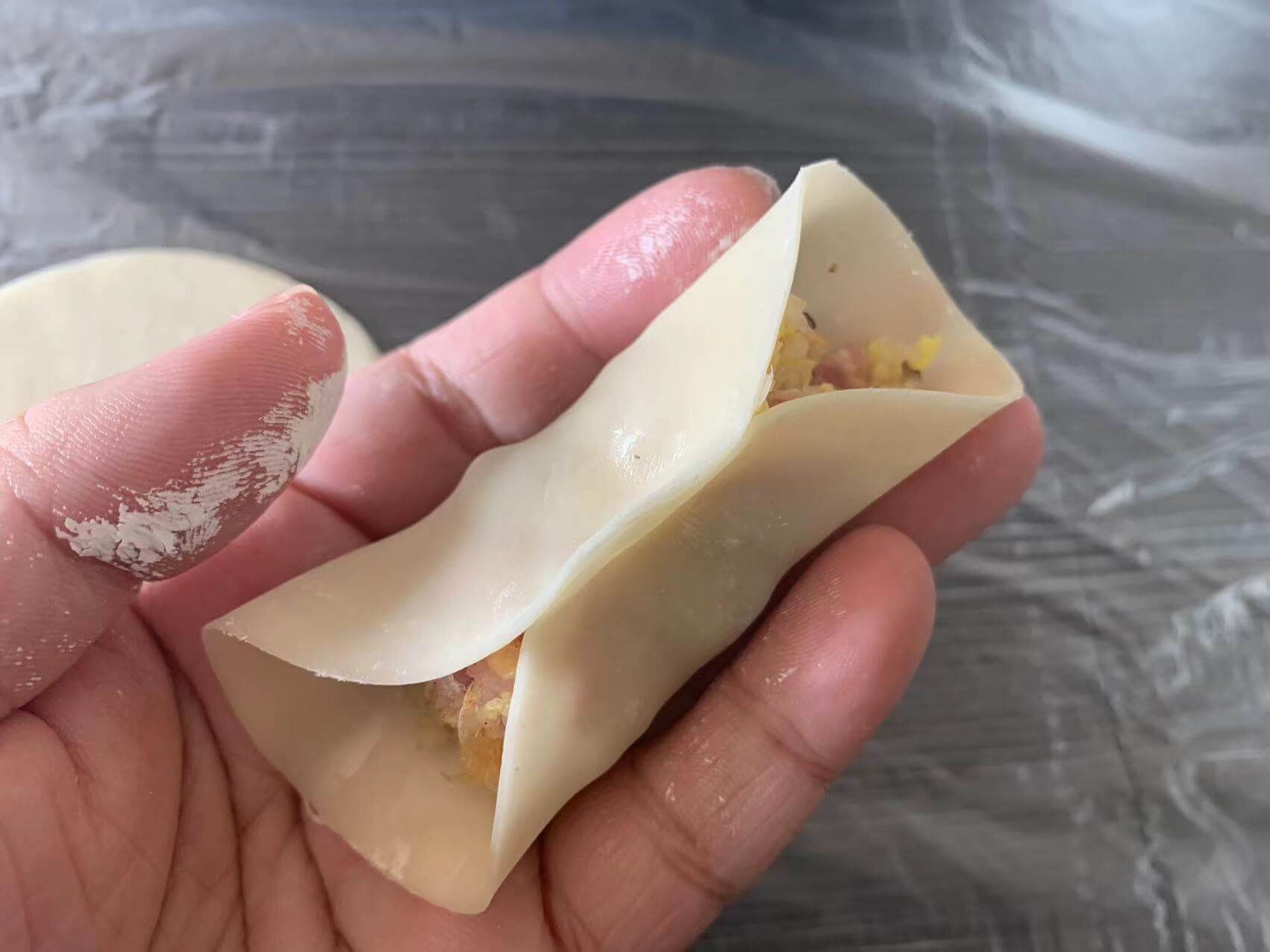 舀一勺馅料放在饺子皮中间